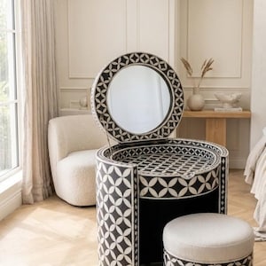 May include: A black and white vanity table with a circular flip-top mirror and a matching cylindrical stool. The furniture features a repeating geometric pattern of interlocking circles and is constructed with a curved, semi-circular base.