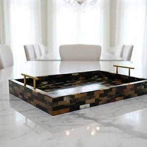 Puede incluir: Una taza de cerámica blanca con un asa negra y el texto "But First, Coffee" en un estilo manuscrito. La taza está sobre una superficie blanca. La taza mide aproximadamente 10 cm de alto.