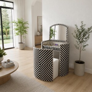 May include: A vanity table and matching stool set featuring a bold black and white chevron pattern. The vanity has a curved, semi-circular design with a hinged lid that opens to reveal a mirror and storage space, paired with a white upholstered stool.
