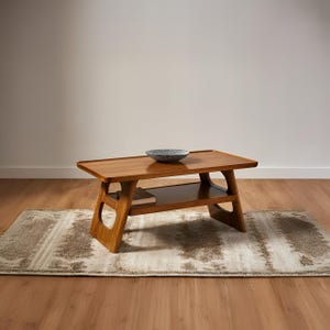 Puede incluir: Una mesa de centro de madera de estilo moderno de mediados de siglo, con un estante inferior. Un cuenco decorativo está sobre la superficie de la mesa. La mesa está sobre una alfombra estampada, y la habitación tiene suelo de madera.