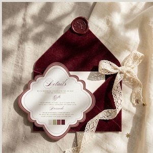 May include: Burgundy velvet envelope with a decorative card and cream lace ribbon. The card has the word "Details" and other text. A wax seal with a bow design is on the envelope.