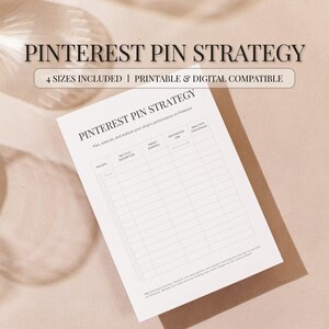 May include: A white printable planner titled "Pinterest Pin Strategy" with a grid for tracking pin performance. The image includes the text "4 Sizes Included | Printable & Digital Compatible". The planner is on a light brown surface.