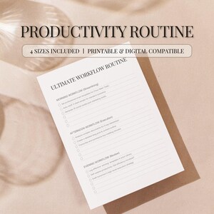 May include: A printable productivity routine checklist with the text "PRODUCTIVITY ROUTINE" and "ULTIMATE WORKFLOW ROUTINE". The checklist is on a white paper with a brown backing, and the background is a light beige color.
