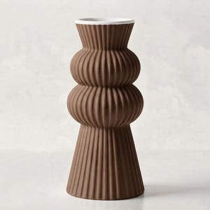 Könnte beinhalten: Eine hohe, braune Vase mit gerippter, vertikaler Textur. Die Vase hat einen breiten, ausgestellten Boden, zwei abgerundete, bauchige Abschnitte in der Mitte und eine ausgestellte Öffnung an der Oberseite mit einem glatten, weißen Innenrand.