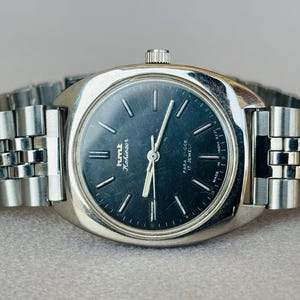 Puede incluir: Reloj de pulsera vintage HMT Kohinoor con caja y correa plateadas. La esfera azul oscuro presenta marcadores y agujas plateadas. La correa es de metal. Un reloj cl&aacute;sico, con un dise&ntilde;o vintage.