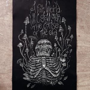 以下が含まれることがあります： 骸骨と肋骨、キノコが描かれた白黒イラスト。上部には「A fair world will grow upon the corpse of the old」というテキストが装飾的なフォントで書かれています。