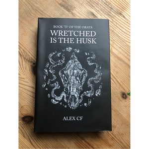 Puede incluir: Portada del libro "Wretched is the Husk", libro dos de "The Orata" de Alex CF. La portada presenta un fondo negro con una ilustración blanca de una calavera rodeada de formas en espiral.