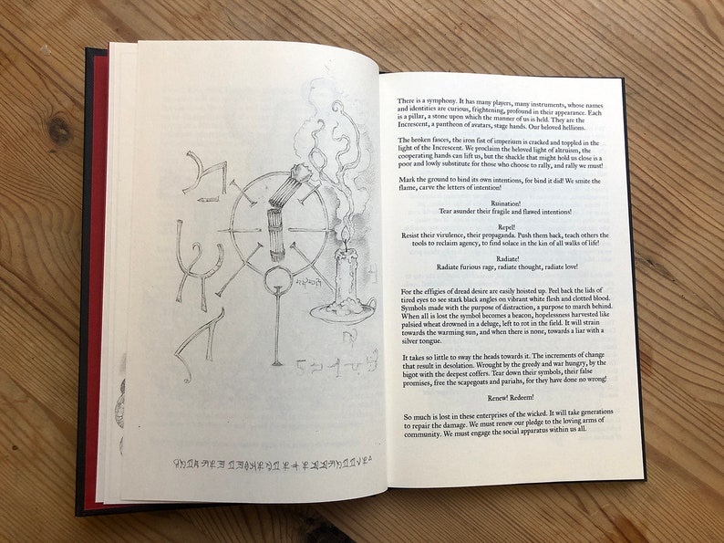 May include: Open book with text and illustrations. The left page has stylized symbols. The right page features text with a candle and a circular diagram. The book's pages are cream-colored, with a black spine and red accents.