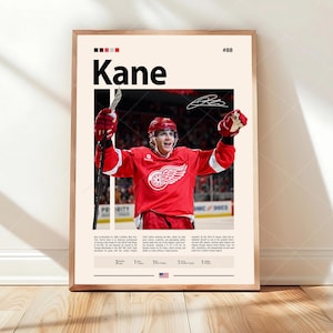 Op de afbeelding: Een verticale poster met een ijshockeyspeler in een rood shirt met een gevleugeld wiel-logo, die een hockeystick vasthoudt en de armen omhoog houdt. De tekst luidt Kane, #88, met een biografie, handtekening en statistieken op een crèmekleurige achtergrond.