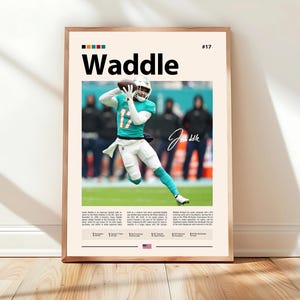 May include: Framed poster featuring a football player in a teal and white uniform throwing a football. The poster has the name "Waddle" in large black letters, with the player's signature and the number 17. The background is a light beige.