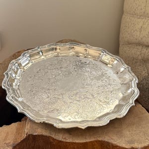 May include: A white ceramic mug with a black handle and the text "But First, Coffee" in a handwritten style. The mug is on a white surface. The mug is approximately 10 cm tall.