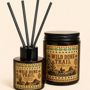May include: A reed diffuser and a soy candle in amber glass jars with black lids. The labels feature the text Wild Dune Trail, a desert landscape illustration with a rider on horseback, and geometric patterns. Four black reeds are in the diffuser.