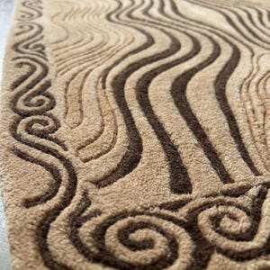 May include: A rectangular rug featuring a textured, carved surface with a pattern of flowing, wavy lines and swirling motifs. The design is rendered in alternating shades of light beige and dark brown, creating a high-contrast, tactile appearance.