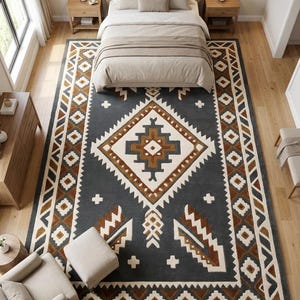 May include: A large rectangular area rug featuring a dark gray background with a central diamond motif and geometric border patterns in cream, brown, and dark gray. The design includes repeating angular shapes and small cross symbols throughout.