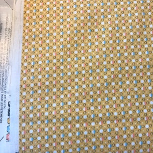Puede incluir: Una tela amarilla con un patr&oacute;n repetitivo de c&iacute;rculos blancos con acentos rosados y azules. La tela tiene texto en el lateral que dice "EINPLAMIRACLE SE PRODUZCA FIERINO CUMPLE CON LOS ESTANDARES FF 3/71 NI 5/74) FLAMMABLE. NE REPONAS STANDARDS D'INFLAMMABELITE POUR LES VETEMENTS UE MAT BARENFANT IFF FLAMMABLE OCE cottons.com".