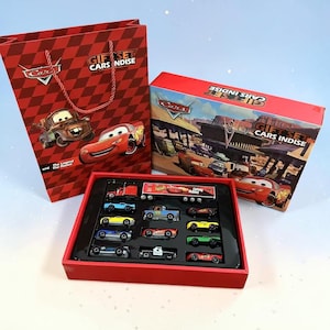 May include: A white ceramic mug with a black handle and the text "But First, Coffee" in a black, handwritten-style font. The mug is on a white surface.