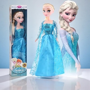 May include: A doll of a character from the movie Frozen, dressed in a blue gown with a sparkly bodice and long sleeves. The doll is in a box with the word "FASHION". The doll has blonde hair and is next to a 3D rendering of the character.