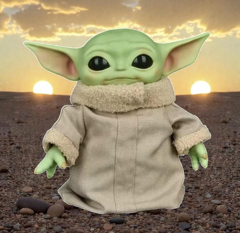 May include: A green-skinned, large-eared character doll wearing a tan coat with a fuzzy collar and cuffs. The doll has large black eyes and small green hands. The background features a sunset with two suns and a rocky surface.