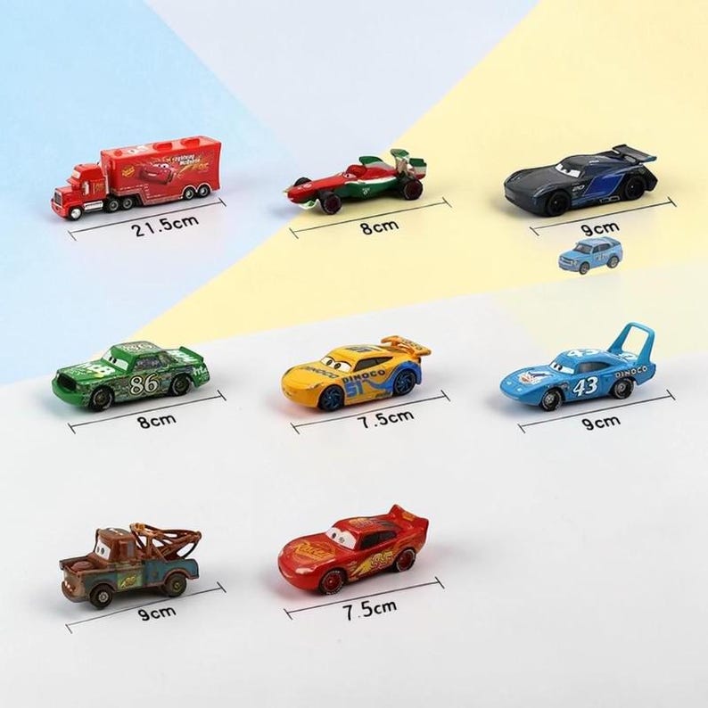 May include: A selection of toy cars in different colours, including red, green, yellow, and blue. The cars vary in size, with the largest being a red truck measuring 21.5 cm long. Other cars include a race car, a tow truck, and a small blue car.