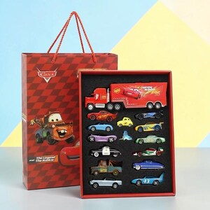 May include: A red gift bag and a red box set featuring toy cars from the film Cars. The gift bag has a Cars logo and a picture of Mater. The box set contains a variety of colourful toy cars.