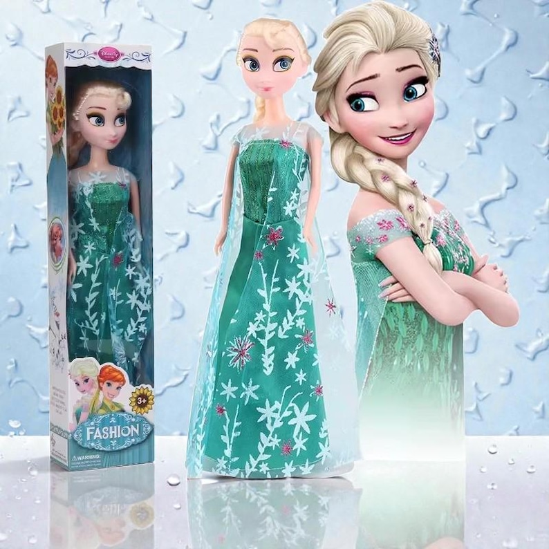 May include: An Elsa doll from the film Frozen, in a green dress with white snowflake and pink floral details. The doll is in a box with the word "FASHION" and the Disney logo. Two other images of Elsa are in the background.