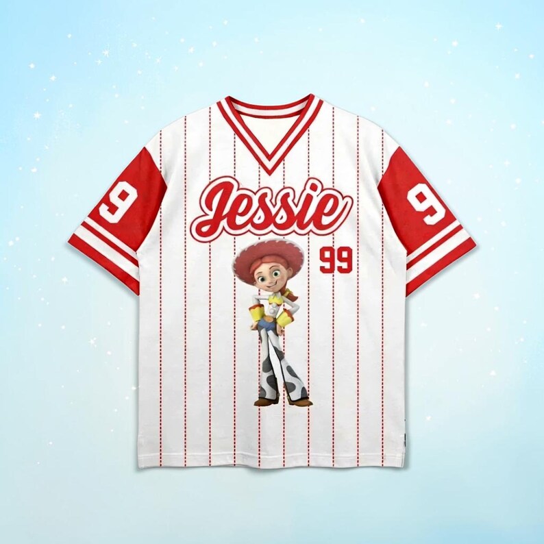 May include: White baseball jersey with red accents, featuring the name "Jessie" in red script and the number "99". The jersey has a cartoon image of Jessie from Toy Story. The sleeves are red with white stripes.