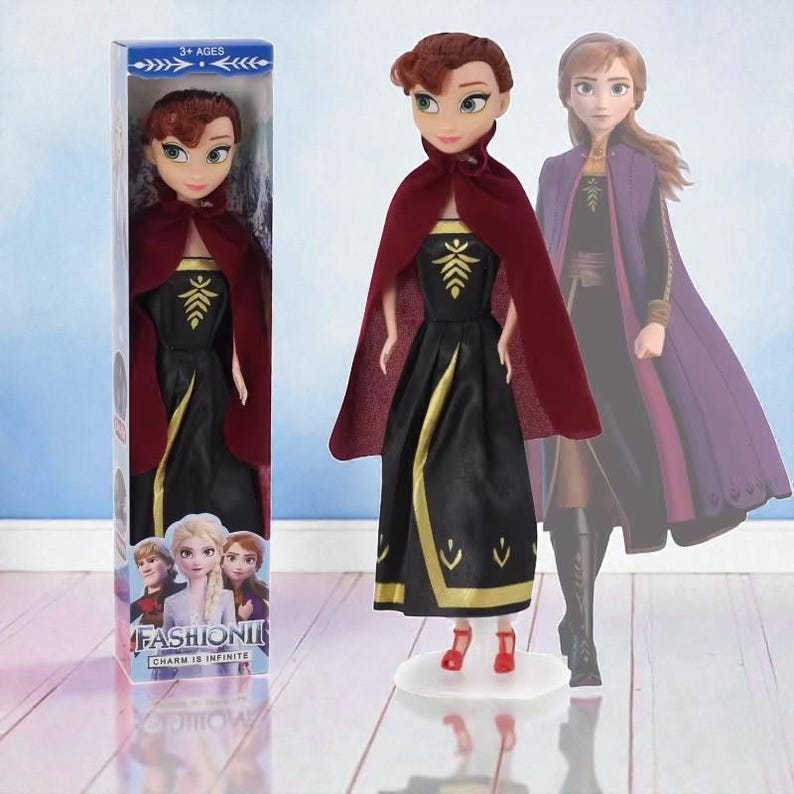 May include: A doll in a black dress with gold detailing and a burgundy cape. The doll has red hair and is on a clear stand. The box features the doll and other characters with the text "FASHION, CHARM IS INFINITE".