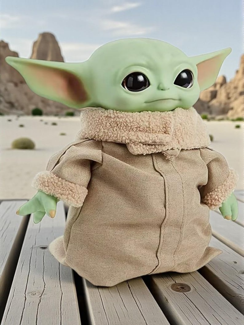 May include: A green-skinned doll with large black eyes and pointed ears, wearing a tan coat with a fuzzy collar and cuffs. The doll is posed on a wooden surface, with a desert landscape in the background.