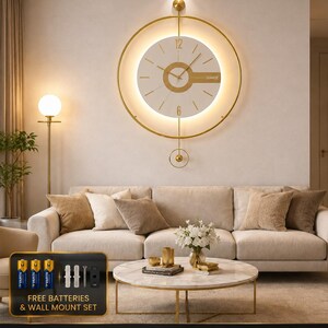 Op de afbeelding: Een ronde wandklok met een gouden metalen frame en een witte wijzerplaat met gouden accenten, de tekst QUARTZ en een geïntegreerde LED-achtergrondverlichting. De klok heeft een slinger, een stil uurwerk op batterijen en een montageset.
