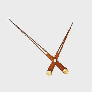 Op de afbeelding: Houten klokwijzers met een warme bruine afwerking en messing accenten. De minutenwijzer is lang en slank, terwijl de uurwijzer korter en breder is. De wijzers zijn ontworpen om op een wijzerplaat te worden gemonteerd.