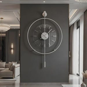 Op de afbeelding: Een moderne, zilverkleurige wandklok met een heldere glazen wijzerplaat en een minimalistisch ontwerp. De klok heeft een cirkelvormige lijst en een slinger, wat een vleugje elegantie toevoegt aan elk interieur. De diameter van de klok is ongeveer 46 cm.