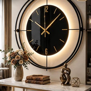 Puede incluir: Un reloj de pared de metal negro de 3 piezas con retroiluminación LED, que presenta un marco circular, una esfera negra con manecillas y números 12 y 6 dorados, y funcionamiento a batería. Incluye movimiento de cuarzo ultra silencioso.
