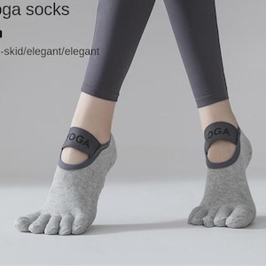 Könnte beinhalten: Graue Yoga-Socken mit Zehentrenner-Design. Die Socken haben ein dunkelgraues Band um den Knöchel mit dem Aufdruck "YOGA". Das Bild enthält auch den Text "Yoga socks" und "Anti-skid/elegant/elegant".