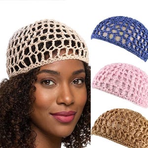 May include: A woman wearing a beige crocheted hat. The image also shows three additional crocheted hats in blue, pink, and brown. The hats have an open, net-like design. The woman has dark curly hair and is smiling.