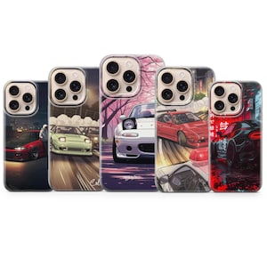 May include: Five phone cases with car-themed illustrations. The cases feature various car designs in different settings, including a red car at night, a green car on a road, and a white car with pink cherry blossoms. The cases have a clear border.