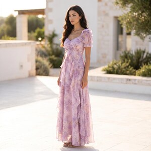 以下が含まれることがあります： 淡いラベンダー色の花柄ロングドレス。パフスリーブ、ハートネックのシャーリング入りボディス、スカートの前面に施された縦方向の段々フリルが特徴で、レイヤード感のある流れるようなシルエットを作り出しています。
