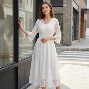 Puede incluir: Vestido blanco de encaje con escote en V y mangas tres cuartos. El vestido presenta un corpi&ntilde;o ajustado y una falda fluida, creando una silueta elegante. Las mangas tienen un dise&ntilde;o acampanado y el vestido llega a media pantorrilla.
