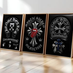 May include: Three rectangular framed wall art prints with black backgrounds and metallic silver embossed designs. The first features Chrome Hearts and Off-White logos. The second shows a cross with a red tongue and MCMXCVIII. The third displays Chrome Hearts emblems.
