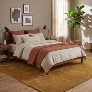 May include: A bedroom with a wooden bed, white bedding, and a rust-coloured throw. The room has a mustard-coloured rug, framed art, and a potted plant. Two black lamps are on the bedside tables. The rug covers an area of approximately 2.5 x 3.5 meters.