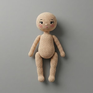 May include: A beige crochet doll featuring a round head with embroidered black eyes, long eyelashes, and pink blush on the cheeks. The doll has a simple, rounded body shape with two arms and two legs, all crafted from a consistent tan yarn texture.