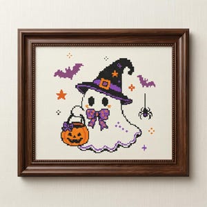 May include: A framed cross-stitch artwork featuring a white ghost wearing a black and purple witch hat and a purple polka-dot bow tie. The ghost holds an orange jack-o'-lantern bucket. The design includes purple bats, a spider, and orange stars.