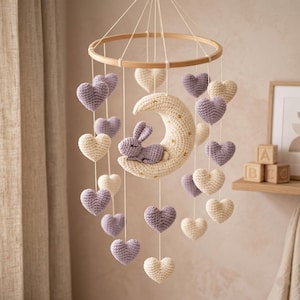 Peut inclure: Mobile pour bébé fait à la main, avec un cercle en bois et des éléments crochetés suspendus. Il comprend un croissant de lune crème avec un lapin lavande, des étoiles dorées et des cœurs lavande et crème alternés. Une charmante décoration de chambre d'enfant.