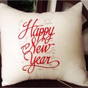 May include: White pillow with red embroidered text that says "Happy New Year".