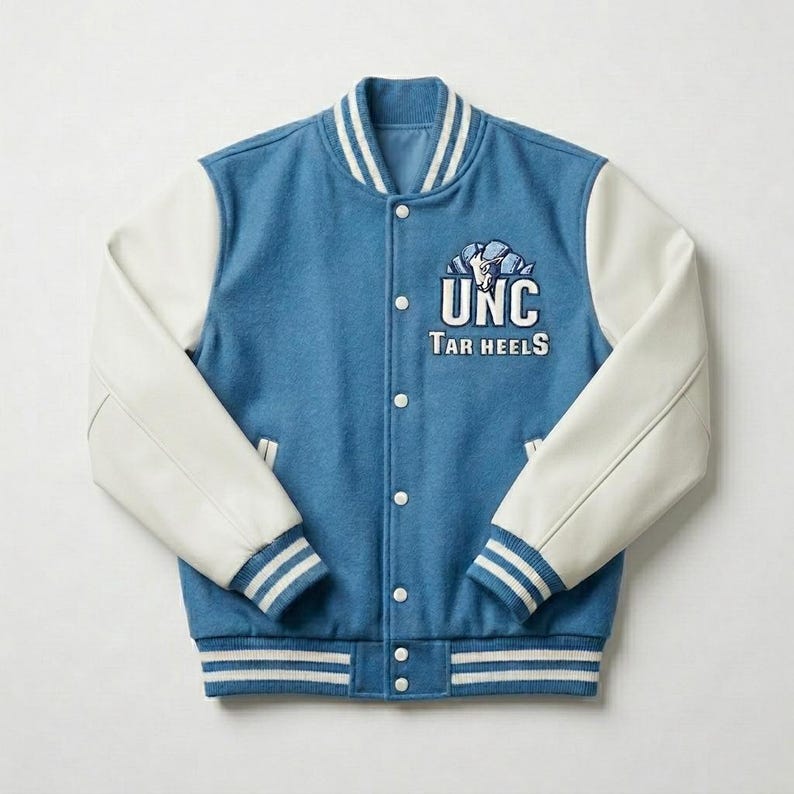 Puede incluir: Una chaqueta universitaria de mezcla de lana azul con mangas blancas, que presenta un logotipo bordado de UNC Tar Heels en blanco y azul en el pecho. La chaqueta tiene un cierre frontal con botones a presi&oacute;n y cuello, pu&ntilde;os y dobladillo acanalados.