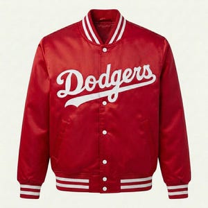 Puede incluir: Una chaqueta universitaria de satén rojo con la palabra Dodgers en letra cursiva blanca en el pecho. La chaqueta cuenta con cierre frontal de botones a presión, mangas largas y ribetes acanalados a rayas blancas en el cuello, puños y bajo.