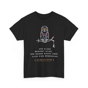 May include: A black short-sleeve t-shirt featuring a white, red, and yellow line-art owl perched on a branch with a crescent moon. Below the owl is the German text: DER KLUGE BEMERKT ALLES, DER DUMME MACHT ÜBER ALLES EINE BEMERKUNG, HEINRICH HEINE.