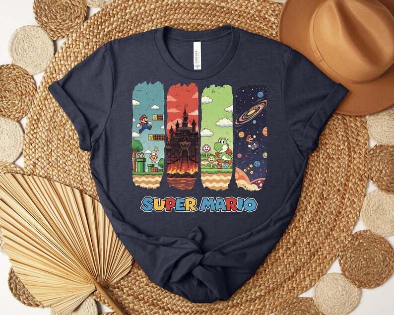 May include: Navy blue t-shirt featuring a colorful Super Mario graphic. The design includes four vertical panels with scenes from the game, including Mario, a castle, Yoshi, and space. The words "SUPER MARIO" are printed in a colorful font.
