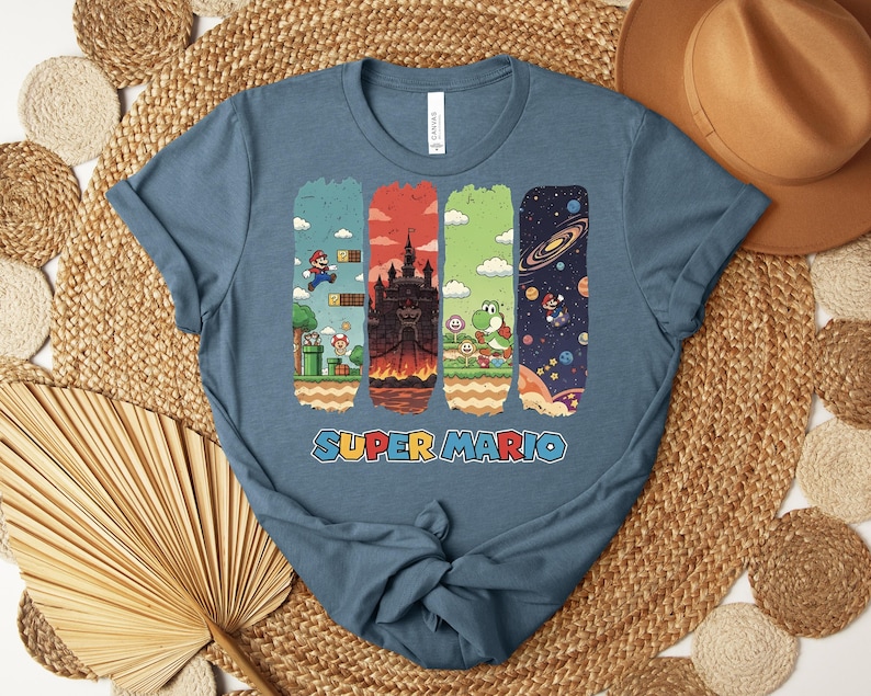 May include: A blue t-shirt featuring a Super Mario design. The graphic includes four vertical panels with scenes from the game, including Mario, a castle, Yoshi, and a space scene. The words "SUPER MARIO" are printed in colorful letters at the bottom.
