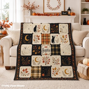Könnte beinhalten: Eine personalisierte Steppdecke mit Patchwork-Design und herbstlichen Motiven wie schwarzen Katzen, Geistern, Mondsicheln, Spinnenweben und Herbstblättern. Das mittlere Quadrat zeigt den Namen Sophia, umgeben von kleinen orangefarbenen Kürbissen.