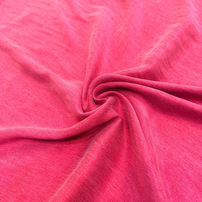 a close-up view of a bright pink fabric, with a noticeable crease in the center.